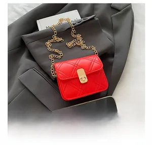 Detailed view of red quilted leather mini bag with gold chain strap and smartphone for scale
