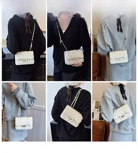 Detail view of white quilted crossbody bag with gold chain strap shown on model