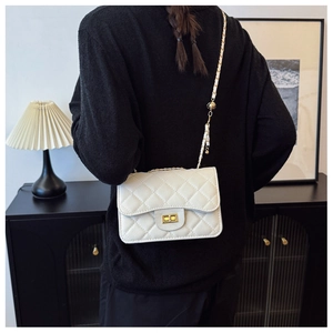 White quilted shoulder bag with gold chain strap and spherical adjuster on a person
