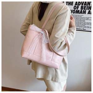Détail du grand sac cabas rose gaufré avec nœud en dentelle porté par un mannequin