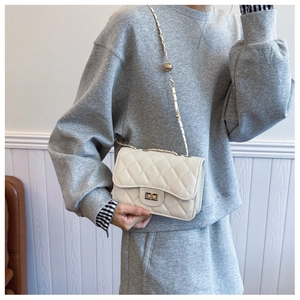 Close-up of beige quilted chain bag with gold buckle on a model wearing grey casual wear