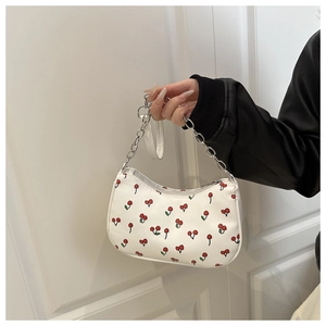 Détail du sac à main blanc à imprimé cerise avec chaîne argentée et fermeture