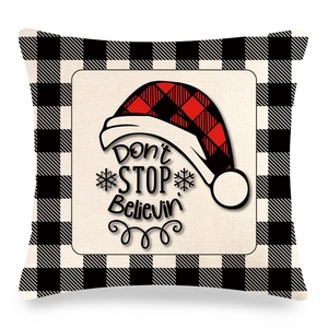 Detail of Christmas buffalo plaid pillow cover with red Santa hat and festive text