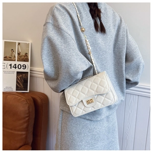 Detailed close-up of white quilted leather crossbody bag with golden chain and clasp