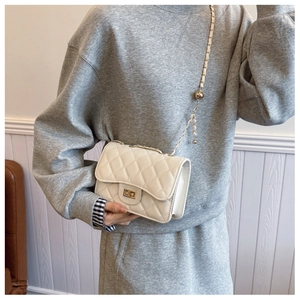 Detailed macro view of the cream quilted leather bag with a gold chain and metal lock