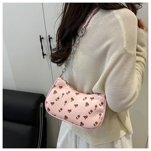 Detail of pink cherry print underarm bag with silver chain strap shown on a model