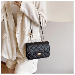 Detail of black quilted crossbody bag with gold rotary lock and adjustable chain strap