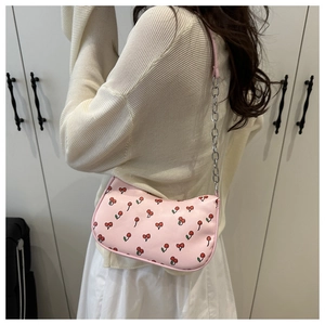 Close-up of pink cherry print hobo bag with silver chain strap worn over the shoulder