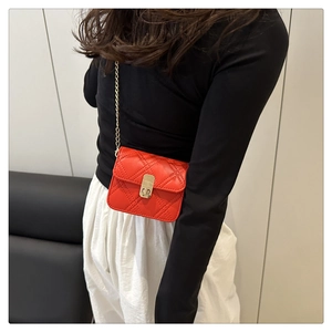 Detail of red quilted leather mini crossbody bag with gold chain strap on model