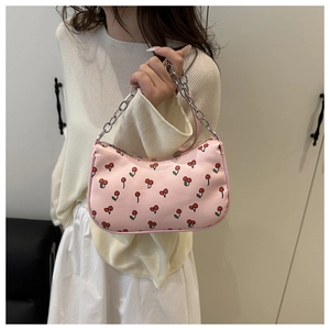 Detailed view of pink cherry print shoulder bag with silver metal chain on model