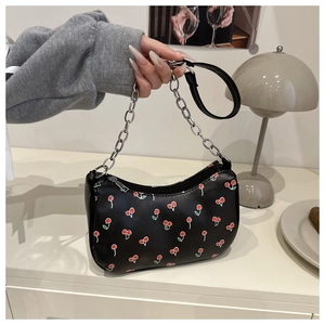 Close-up of black half-moon bag with cherry print and silver metal chain strap