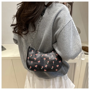Detail of black cherry print shoulder bag with silver chain strap on model's shoulder