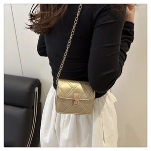 Detail of gold quilted mini crossbody bag with metal chain strap and twist lock