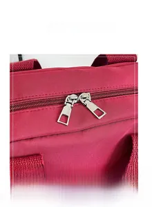 Detail of silver dual zippers on burgundy fabric texture of a casual pillow bag