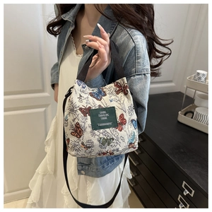 Detail view of mini floral bucket bag with butterfly pattern and green woven label