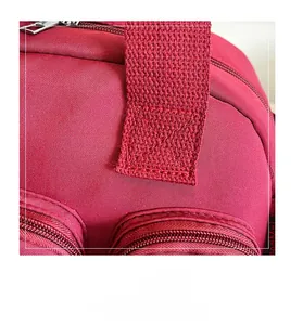 Close-up of deep red nylon bag showing reinforced stitching and metal zipper detail