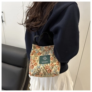 Detail view of small floral tapestry tote bag worn by a model in a casual setting