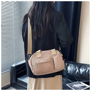 Detail of canvas bag showing dual front zip pockets and adjustable shoulder strap