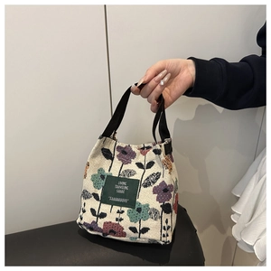 Detail of floral tapestry tote bag with a green patch and sturdy black handles