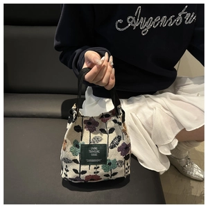 Detail shot of mini canvas bucket bag with vintage floral patterns and woven green label