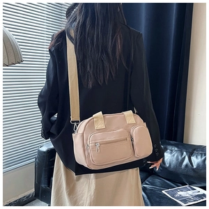 Detail of beige nylon crossbody bag featuring dual front zip pockets and wide strap