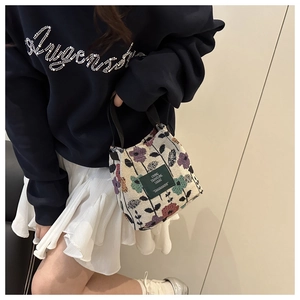 Detail of floral knit tote bag featuring vintage flower patterns and woven logo label