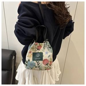 Detail of vintage floral embroidery and brand label on cream canvas bucket bag