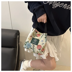 Detail view of floral canvas tote bag with retro patterns and sturdy black handles