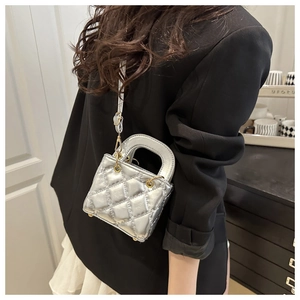 Chic silver quilted mini handbag shown with a silver shoulder strap and metallic finish