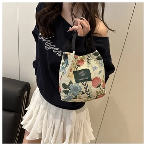 Close-up of vintage floral tapestry handbag with green label worn with a casual outfit