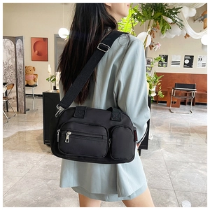 Detail of black nylon crossbody bag with multi-zipper pockets and adjustable wide strap