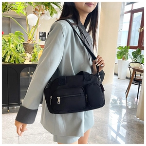 Detail view of black nylon crossbody bag with multiple pockets and silver zippers