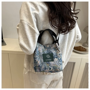 Close-up of floral jacquard bucket bag with woven handles and minimalist brand tag