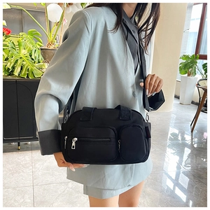 Detail view of a black nylon Boston bag with multiple zipper pockets on a crossbody strap