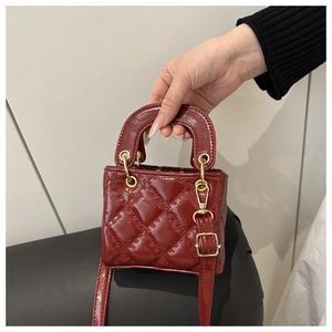 Detail of dark red mini quilted patent leather handbag with golden hardware
