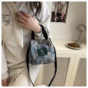 Close-up of floral jacquard bucket bag with green label and black woven handle