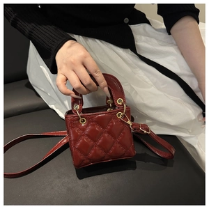Detail of red quilted mini handbag with glossy finish and gold ring handle for women