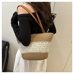 Detail of hand-woven straw tote bag with bi-color pattern and synthetic leather straps