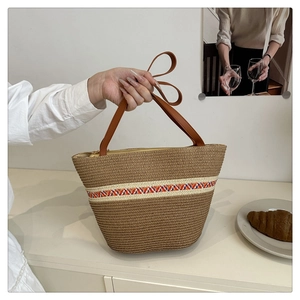 Detail der gewebten Strandtasche mit bunten Wellenmustern und braunen Ledergriffen