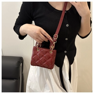 Detail of red quilted patent leather mini bag with gold hardware and lady style design
