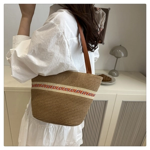 Detailansicht der Stroh-Stofftasche mit Ethno-Muster-Gurt an einem weiblichen Model