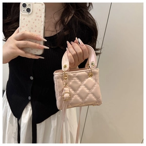 Gros plan du mini sac matelassé rose bébé avec ferrures dorées et poignées rondes
