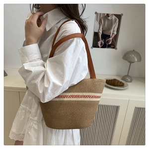 Detail of woven beach tote with ethnic embroidery and brown leather shoulder strap