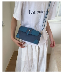 Blue woven fabric and matte leather baguette bag with gold metal buckle shown on a model