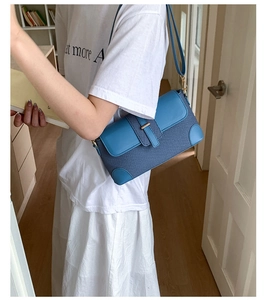 Close-up of blue baguette bag featuring mixed textures and golden metal buckle detail
