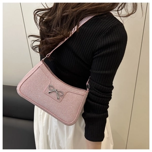 Side view of pink sequin shoulder bag featuring a silver metal bow and adjustable strap