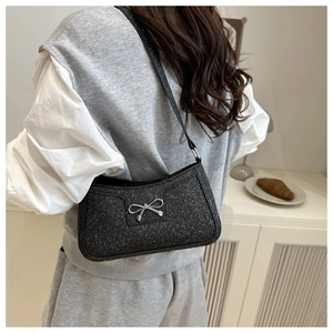 Detail of black sequined shoulder bag with a silver metal bow and shiny texture