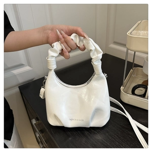 Detail of white pleated cloud handbag with leather texture and fashion logo print