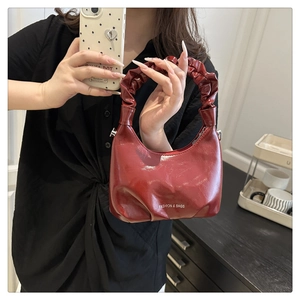 Detail view of burgundy bucket bag with ruched handle and glossy oil wax leather finish