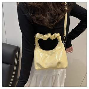 Close-up of the light yellow glossy leather pleated handle and silver metal hardware detail